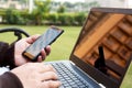 Man is holding smartphone in hand with laptop Royalty Free Stock Photo