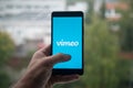 Man holding smartphone with Vimeo logo with the finger on the screen