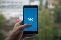 Man holding smartphone with Vkontakte logo with the finger on the screen