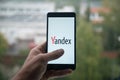 Man holding smartphone with Yandex with the finger on the screen