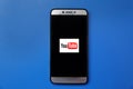 Youtube logo on smartphone screen on blue background. Man holding smartphone with Youtube logo on the screen. Royalty Free Stock Photo
