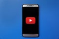 Youtube logo on smartphone screen on blue background. Man holding smartphone with Youtube logo on the screen. Royalty Free Stock Photo