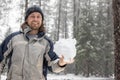 A man is holding a snow ball in his hand while wearing a blue and gray jacket Royalty Free Stock Photo