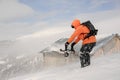 Man holding the snowboard in hands on the hill near the house