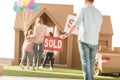 man holding sold signboard with young family moving into new cardbord house Royalty Free Stock Photo