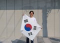 The man holding South Korea flag in his hands on grey background