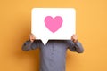 Man holding speech bubble with pink heart on yellow backdrop