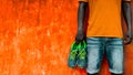 Man holding sport shoes in his hand on orange wall