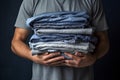 Man holding stack of clothes for reuse, donation or moving. Renewable concept, Laundry day, recycling, charity. Reuse, recycling