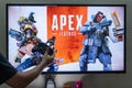 Man holding steam controller in front of a screen loading apex legends a massively online multiplayer shooter game with