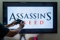 Man holding steam controller in front of a screen loading a game of assassin's creed an action adventure game by ubisoft