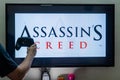 Man holding steam controller in front of a screen loading a game of assassin's creed an action adventure game by ubisoft