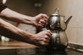 Man holding a steaming stainless kettle on the stove