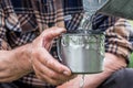 Man is holding a steel mug and a well water is pouring from a bucket Royalty Free Stock Photo