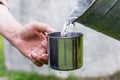 Man is holding a steel mug and a well water is pouring from a bucket Royalty Free Stock Photo