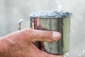 Man is holding a steel mug and a well water is pouring from a bucket Royalty Free Stock Photo