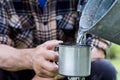 Man is holding a steel mug and a well water is pouring from a bucket Royalty Free Stock Photo