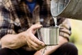 Man is holding a steel mug and a well water is pouring from a bucket Royalty Free Stock Photo