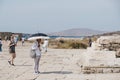 Man holding a sun umbrella looks at the ruins at Greek island of Delos