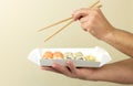 Take away food concept, man holding sushi set and eating Japanese food by chopsticks Royalty Free Stock Photo