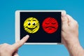Man holding a tablet device showing happy and sad emojis Royalty Free Stock Photo