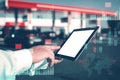 Man holding tablet mockup with white screen on background gas station with fuel dispensers on technological background. Graph of Royalty Free Stock Photo