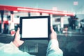 Man holding tablet mockup with white screen on background gas station with fuel dispensers on technological background. Graph of Royalty Free Stock Photo