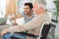 man holding tablet for older man in wheelchair Royalty Free Stock Photo