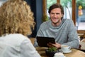Man holding tablet PC while looking at woman in coffee shop Royalty Free Stock Photo