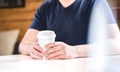 Man holding take away coffee cup in hands on table in cafe. Royalty Free Stock Photo