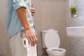 Man holding tissue paper roll standing in front of toilet. Men have abdominal, diarrhea or waist pain. Stomach health problem Royalty Free Stock Photo