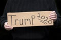 Man holding Trump 2020 political election homemade sign with dark background