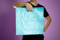 A man holding a turquoise plastic bag. Close up. Isolated on grey background