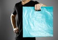 A man holding a turquoise plastic bag. Close up. Isolated on grey background
