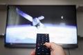 Man holding remote control and watching satellite scene Royalty Free Stock Photo