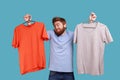 Man holding two hangers with gray and orange T-shirts, choosing outfit for going for a walk. Royalty Free Stock Photo