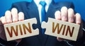 Man holding two puzzles with Win-Win words. A negotiation strategy makes all parties succeed. Mutual benefit and good contract Royalty Free Stock Photo