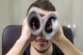 Man holding two twisted roll newspaper. Metaphor or allegory with binoculars. Selective focus on the eyes Royalty Free Stock Photo