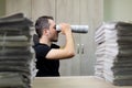 Man holding two twisted roll newspaper. Metaphor or allegory with binoculars. Selective focus on the face