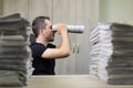 Man holding two twisted roll newspaper. Metaphor or allegory with binoculars. Selective focus on the face Royalty Free Stock Photo