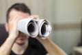 Man holding two twisted roll newspaper. Metaphor or allegory with binoculars. Selective focus on newspapers