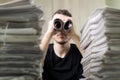 Man holding two twisted roll newspaper. Metaphor or allegory with binoculars. Selective focus on newspapers