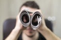 Man holding two twisted roll newspaper. Metaphor or allegory with binoculars. Selective focus on newspapers
