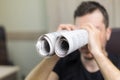 Man holding two twisted roll newspaper. Metaphor or allegory with binoculars. Selective focus on newspapers Royalty Free Stock Photo