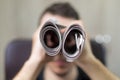 Man holding two twisted roll newspaper. Metaphor or allegory with binoculars. Selective focus on newspapers