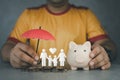 Man holding umbrella with a piggy bank and paper family. Insurance concept Royalty Free Stock Photo