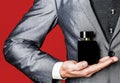 Man holding up bottle of perfume. Men perfume in the hand on suit background. Fragrance smell. Men perfumes. Fashion Royalty Free Stock Photo