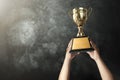 a man holding up a gold trophy cup with grunge wall background c Royalty Free Stock Photo