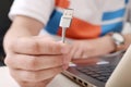 Man holding USB cable in hand with laptop on table Royalty Free Stock Photo