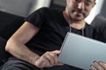 Man holding using digital tablet and headphones sitting on a sofa. Online education, working, video call